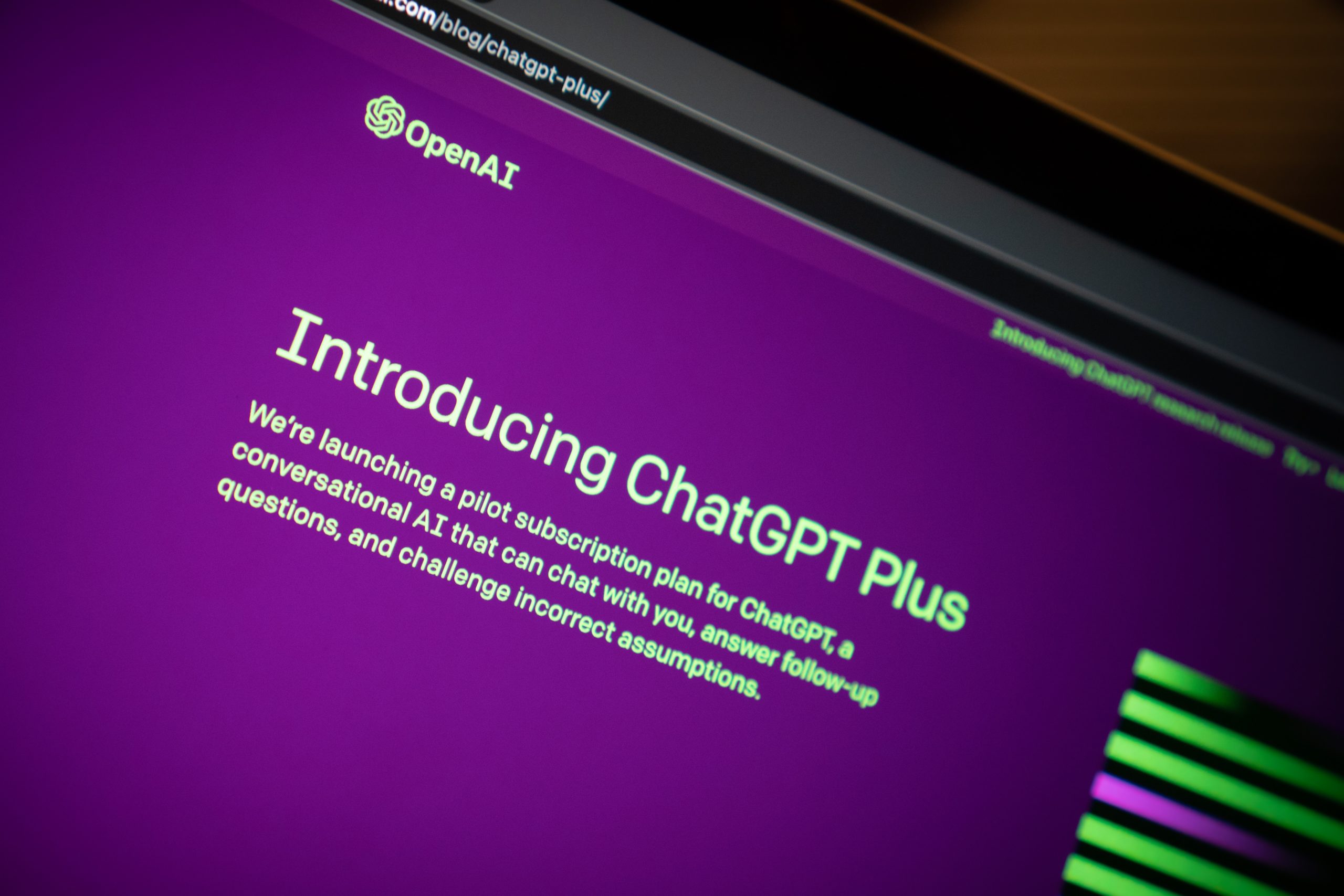 A section of a laptop screen shows a browser pointed to OpenAI's introduction of ChatGPT. The website is purple with light green text.
